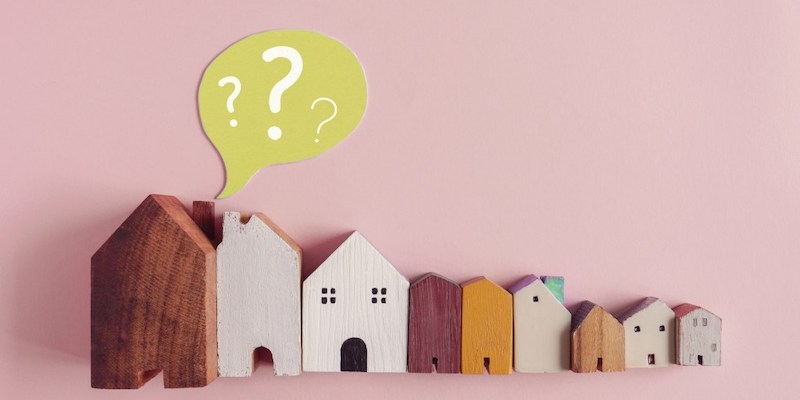 Image of model houses with a question mark above them