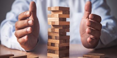 Man protecting risky Jenga stack... Buying property at auction comes with risks! 