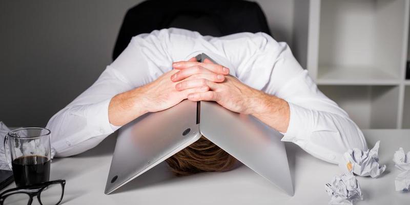 Image of a frustrated man with a laptop over his head after his sale has just fallen through
