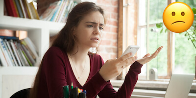 Frustrated lady looking at phone after house sale fallen through
