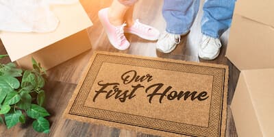 Am I still a first time buyer after I inherit a property? Couple standing by door mat that says "first time buyer".