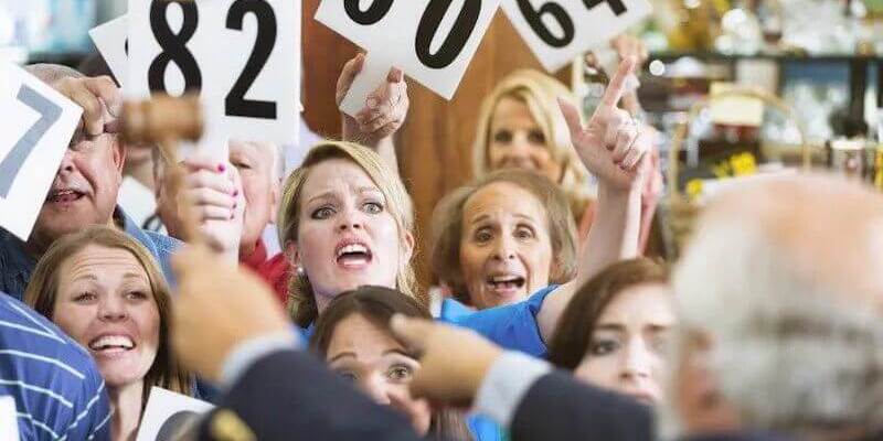Image of a crowded auction room with people bidding on a property.