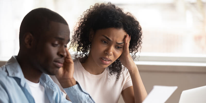 How do I transfer ownership of an inherited property? Couple sat looking at paperwork looking confused.