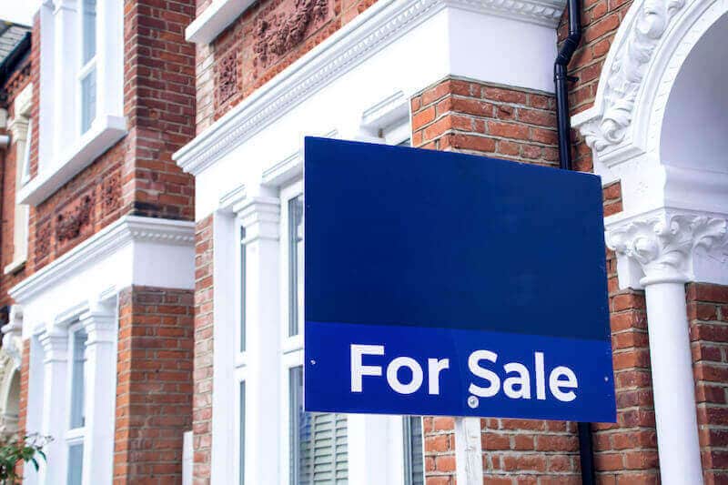 A picture of a for sale sign outside a terraced house.