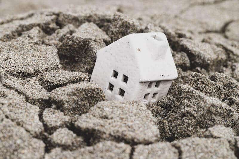 A toy house subsiding into ground.