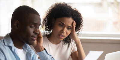 Couple sat together looking confused at a piece of paper. Why you should know the difference between subsidence and settlement.