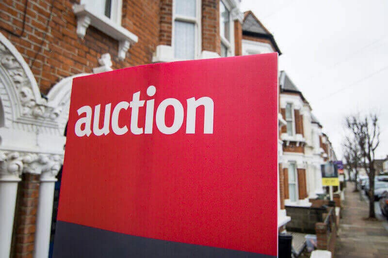 A picture of an auction for sale sign outside a property.
