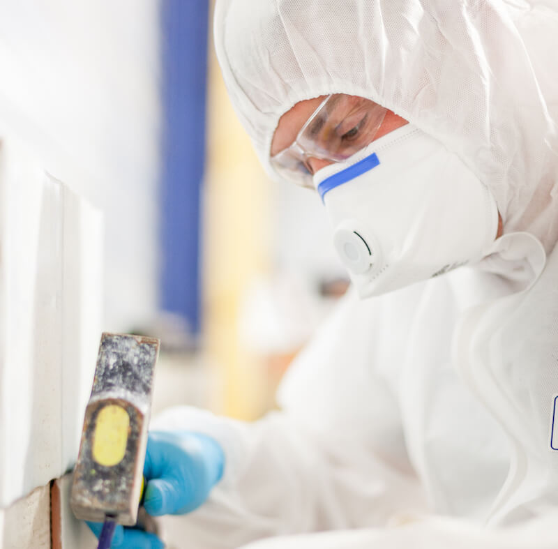 An asbestos surveyor taking a sample of building materials during an asbestos survey.