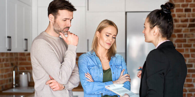 Couple looking concerned in a meeting with estate agent. Can I sell an underpinned house? 2 best ways to sell and my top tips.