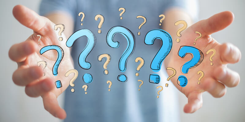 Man on blurred background presenting hand drawn question marks in his hand. Underpinned Houses, the complete guide. Top 11 most popular questions.