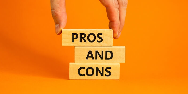 Pros and cons of selling your house quickly to a house-buying company. Image of the words "pros and cons" on 3 wooden blocks, with a hand putting them into place.