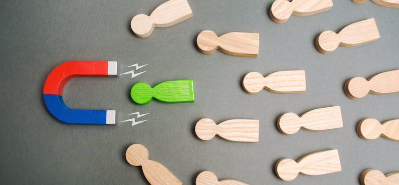 Picture of a magnet attracting a green object out of all the rest. It symbolises finding the best company that buys your house