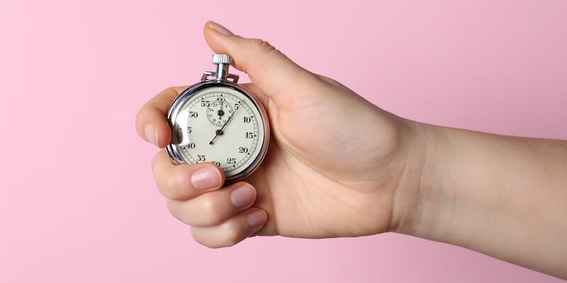 Woman holding stopwatch clock. How long does it take to sell a house by modern auction?