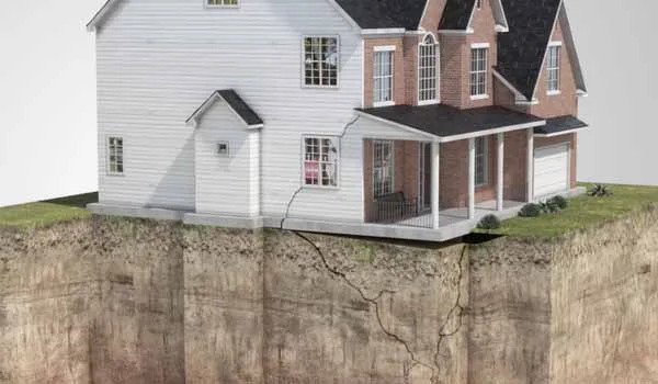 Image of part of the land under a property cracking away, and a mirrored crack appearing on the property above it.