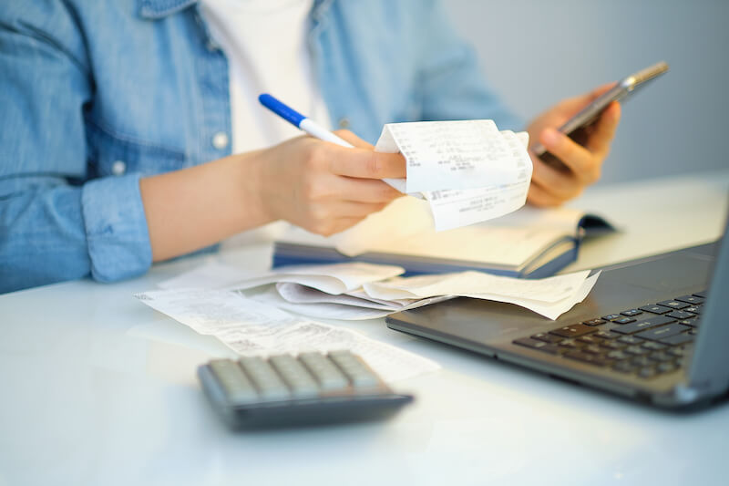 A person holding receipts and a calculator.
